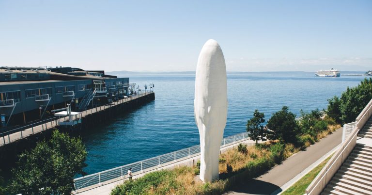 Waterfront sculpture near pier and cruise ship