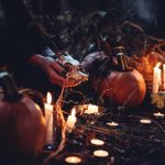 Pumpkins and candles with skull in forest scene.