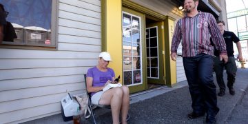 Woman sitting outside, reading on a chair.