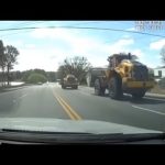 Construction vehicles on a road with trees.