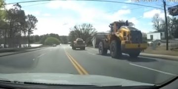 Construction vehicles on a road with trees.