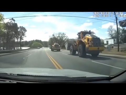 Construction vehicles on a road with trees.