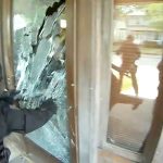 Police breaking glass door during operation