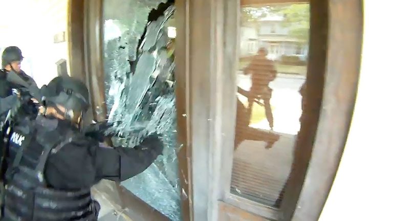 Police breaking glass door during operation