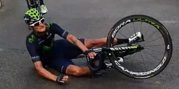 Cyclist falls during race, lying on the road.