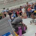 Crowd watches altercation in store aisle.