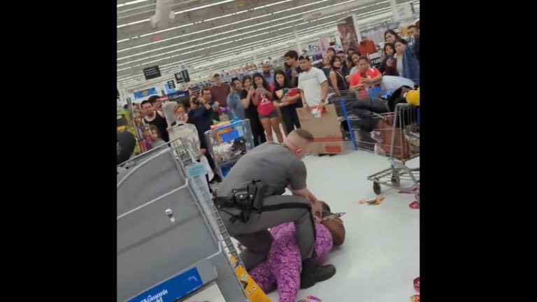 Crowd watches altercation in store aisle.