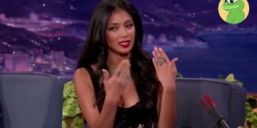 Woman speaking on talk show, gesturing with hands.