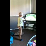 Child playing a tennis video game indoors.