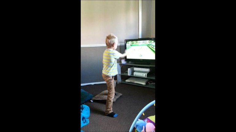 Child playing a tennis video game indoors.