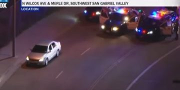 Police cars surround vehicle on nighttime road.