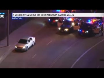 Police cars surround vehicle on nighttime road.