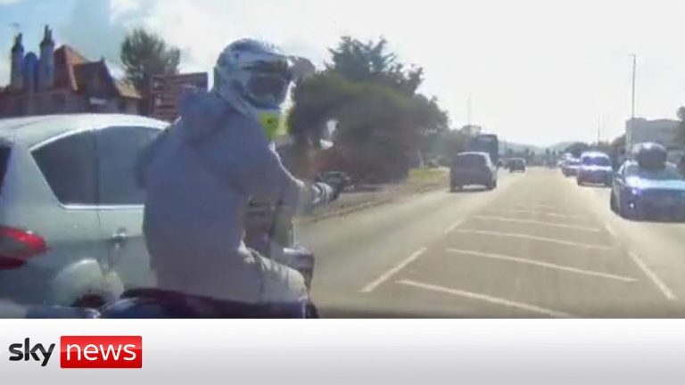 Motorcyclist on busy road with cars.