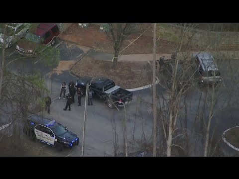 Police activity around parked vehicles on road.