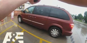 Person pointing camera at red van in parking lot.