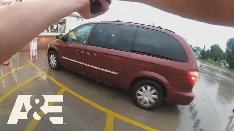 Person pointing camera at red van in parking lot.