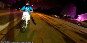 Motorcyclist riding down street at night.