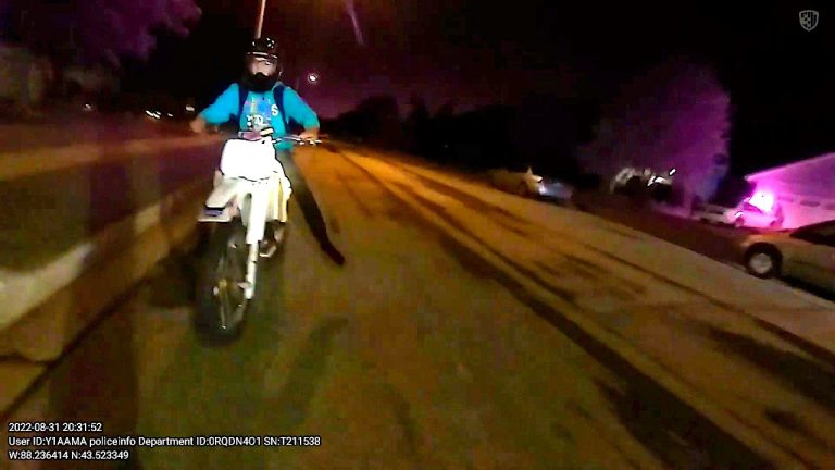 Motorcyclist riding down street at night.