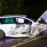 Severely damaged car after night accident on road.