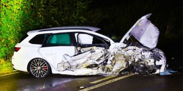 Severely damaged car after night accident on road.