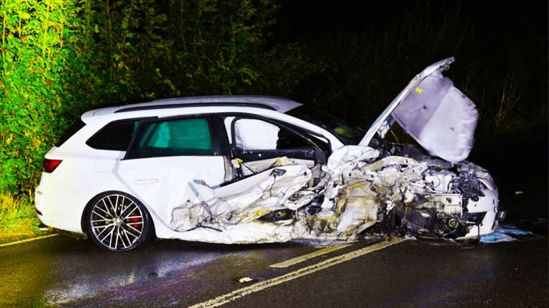 Severely damaged car after night accident on road.