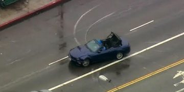 Convertible car driving on wet urban street