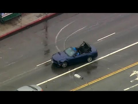 Convertible car driving on wet urban street