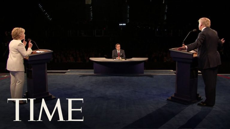 Politicians debate on stage with moderator present.