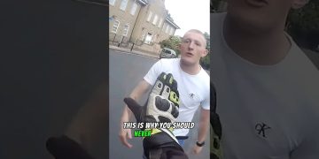 Motorcyclist gesturing towards a man on the street.