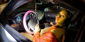 Person in car with pink steering wheel.