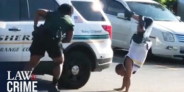 Person doing handstand near police car