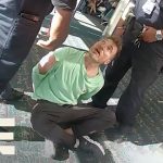 Man in handcuffs with two officers at airport.