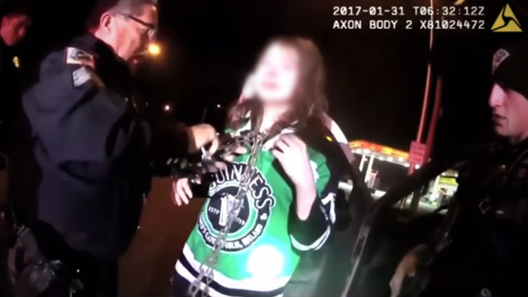 Police officers assisting a person in a hockey jersey.