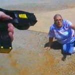 Taser aimed at woman on ground.