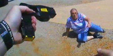 Taser aimed at woman on ground.