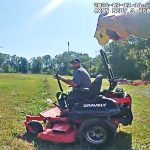 Person operating lawn mower in a field