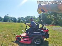 Person operating lawn mower in a field