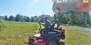 Person operating lawn mower in a field