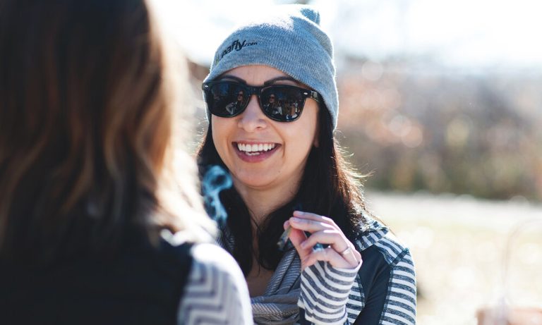 Smiling woman in sunglasses and gray beanie