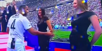 Soccer player greeting people on red carpet.