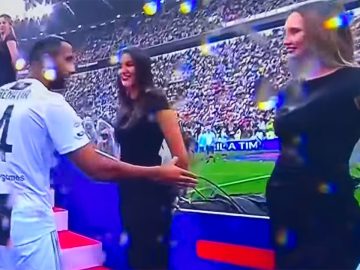 Soccer player greeting people on red carpet.