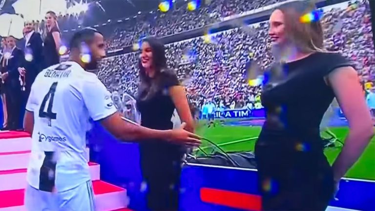 Soccer player greeting people on red carpet.