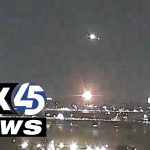 Nighttime cityscape with bright lights and news logo.