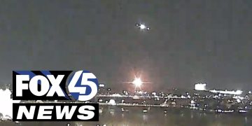 Nighttime cityscape with bright lights and news logo.