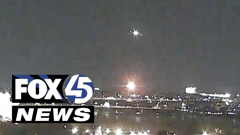 Nighttime cityscape with bright lights and news logo.