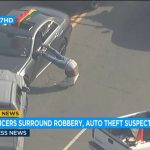 Police surround suspect's car during robbery investigation.