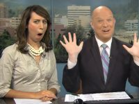 Two amused TV anchors at news desk.