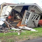 Man observing house destroyed by hurricane damage.