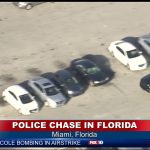 Police chase in Miami parking lot, aerial view.