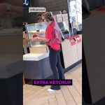 Woman holds ketchup in fast-food restaurant.